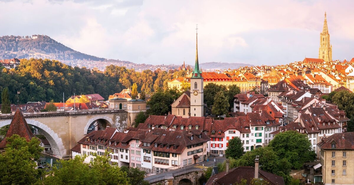 Hübsche europäische Stadt mit mythologischen Statuen und einem türkisfarbenen Fluss, auf dem die Einheimischen treiben